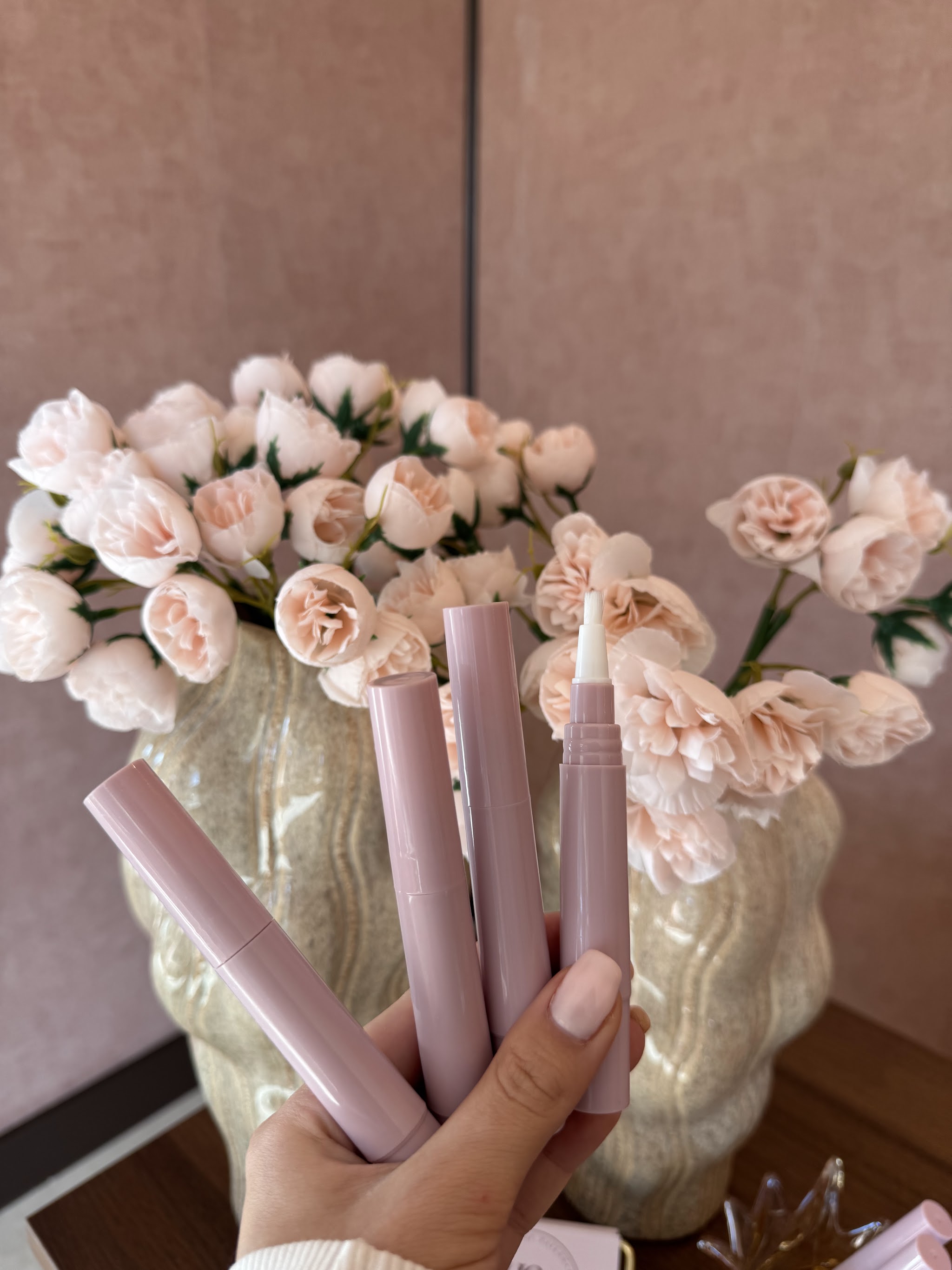 Lash- en browserums in roze verpakking voor een vaas met bloemen in de salon