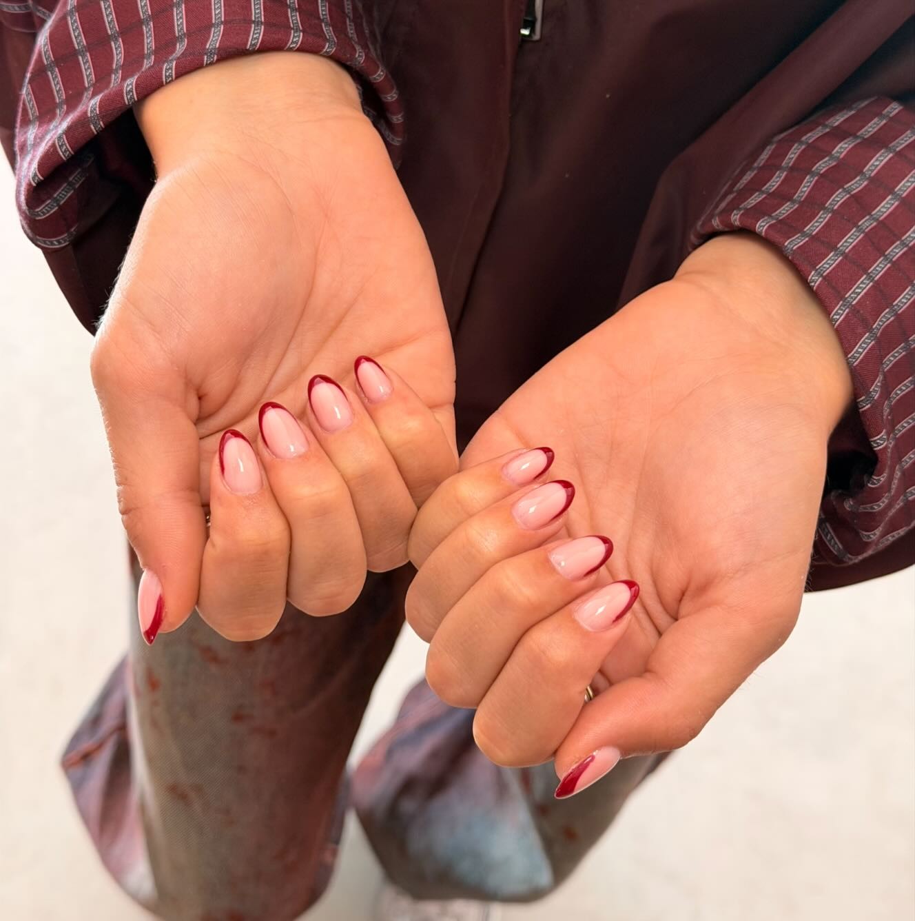 Twee handen met rode French nagels, werk van Noaréa Beauty